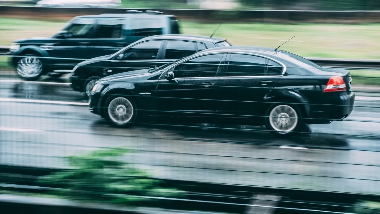 A couple of black cars are parked on the side of the road